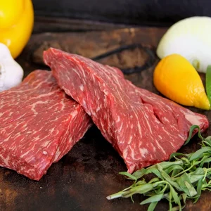 Picture of beef surrounded by vegetables, fruit and herbs on a cutting board