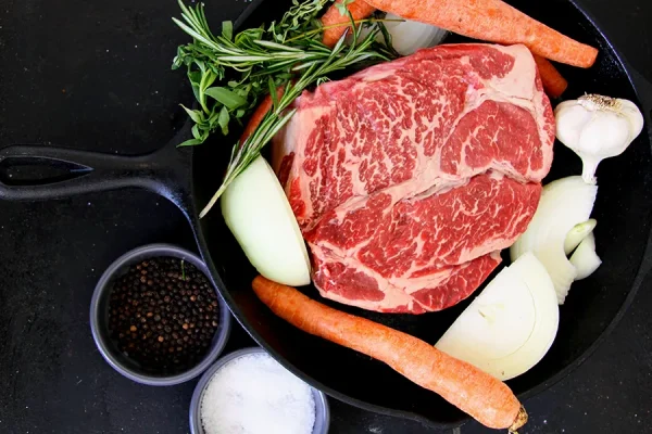 chuck roast surrounded by veggies in a cast iron pan