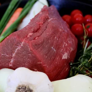 eye of round roast surrounded by veggies in a cast iron pan