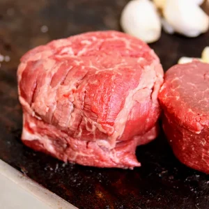 Picture of beef surrounded by herbs on a cutting board