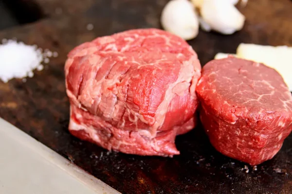 Picture of beef surrounded by herbs on a cutting board