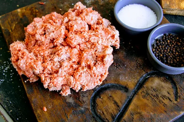 ground beef with peppercorns and salt on a Park Ranch branded JP cutting board