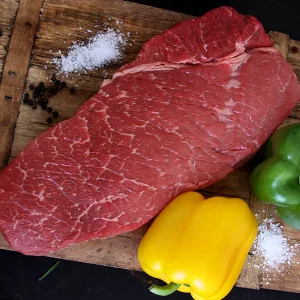 Top london roast surrounded with bell peppers and salt on a Park Ranch branded JP cutting board