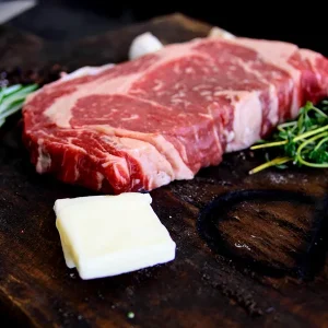 Picture of beef surrounded by spices on a cutting board and some cheese