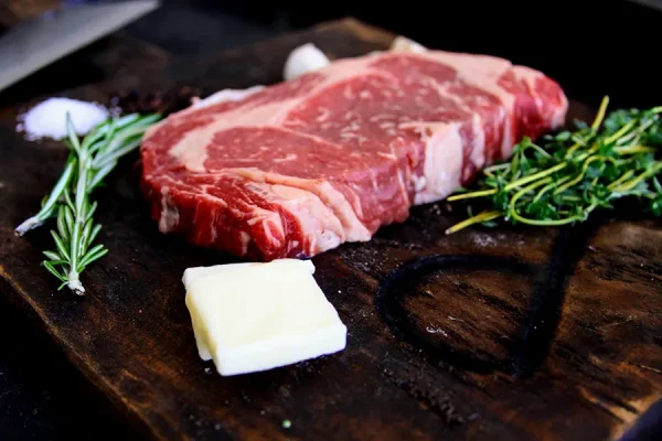 Picture of beef surrounded by spices on a cutting board and some cheese