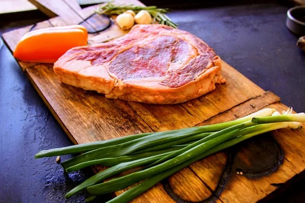 Picture of beef surrounded by vegetables on a cutting board