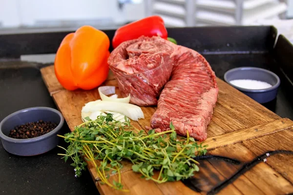 Picture of skirt steak surrounded by vegetables, herbs and spices on a cutting board