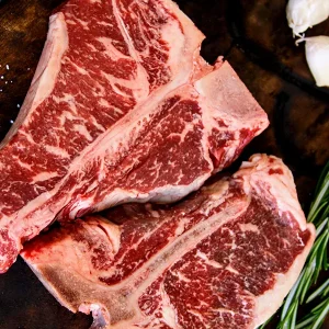 Picture of T-bone steaks on a cutting board with herbs and spices on a cutting board