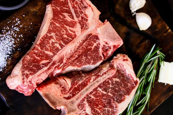 Picture of T-bone steaks on a cutting board with herbs and spices on a cutting board