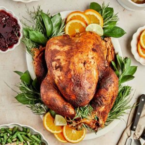 smoked Diestel Family Ranch turkey on a cutting board with garnish and stuffing ingredients