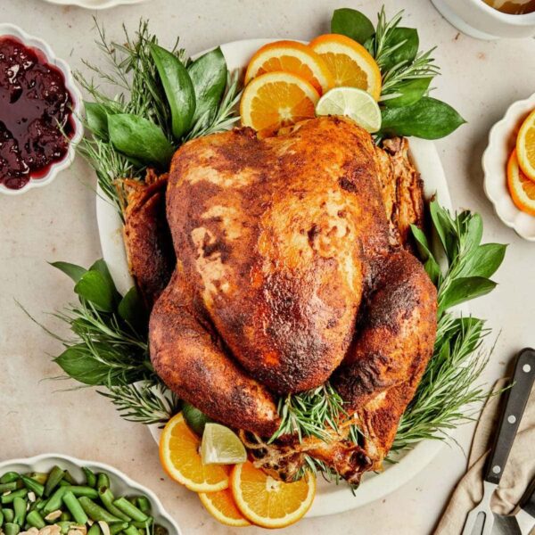 smoked Diestel Family Ranch turkey on a cutting board with garnish and stuffing ingredients