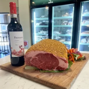 ready-to-cook seasoned boneless prime rib for the holidays displayed on a cutting board with garnishes next to a Danzante Chianti