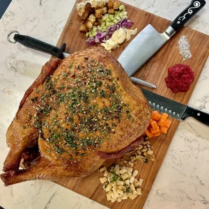 smoked Diestel Family Ranch turkey on a cutting board with garnish and stuffing ingredients